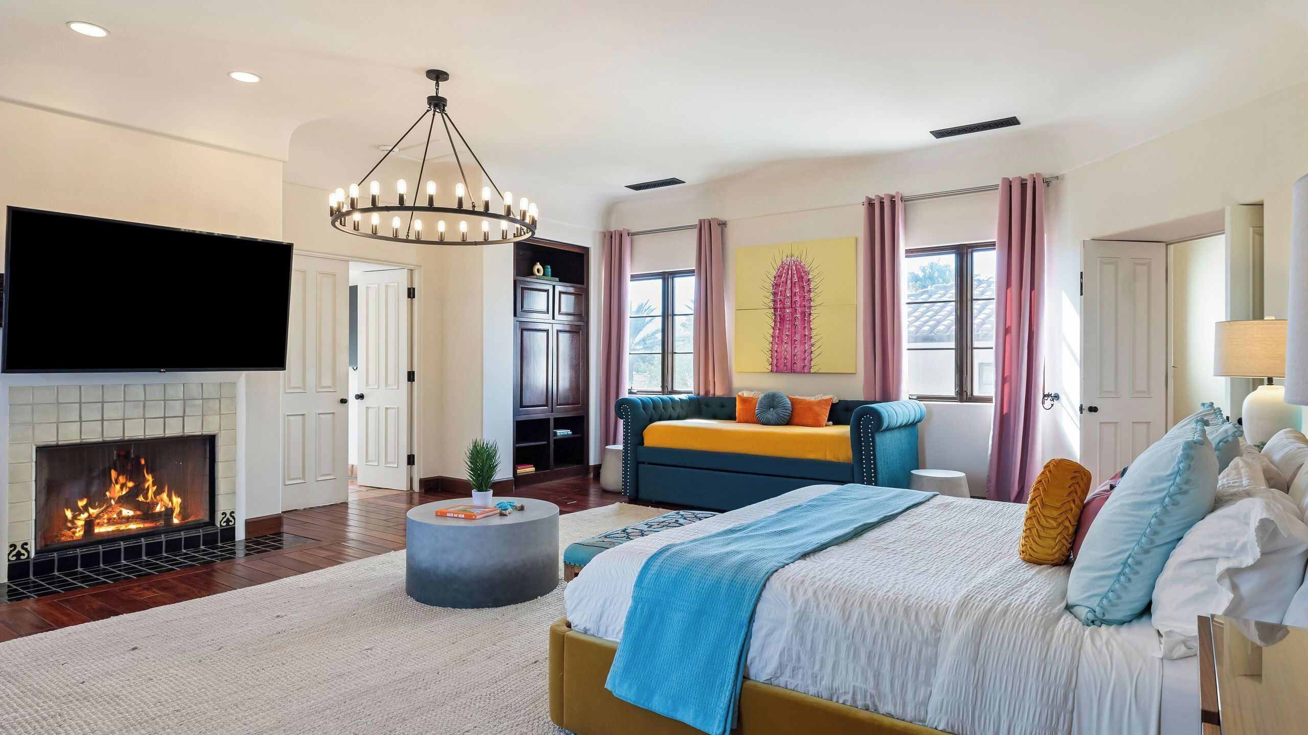 A bedroom with a fireplace, a bed, a sofa, and a television.