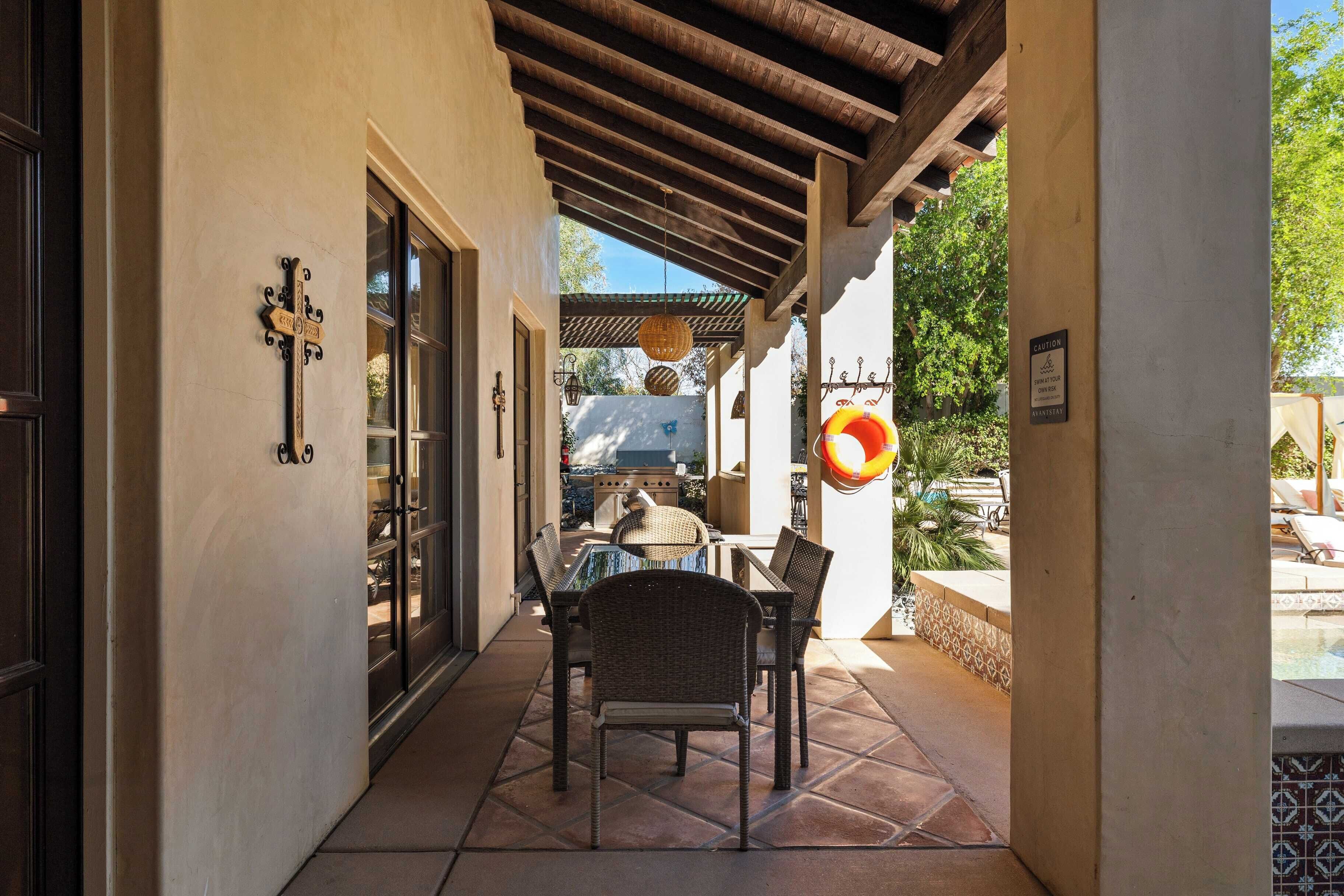 A covered patio area with wicker furniture and a poolside setting.