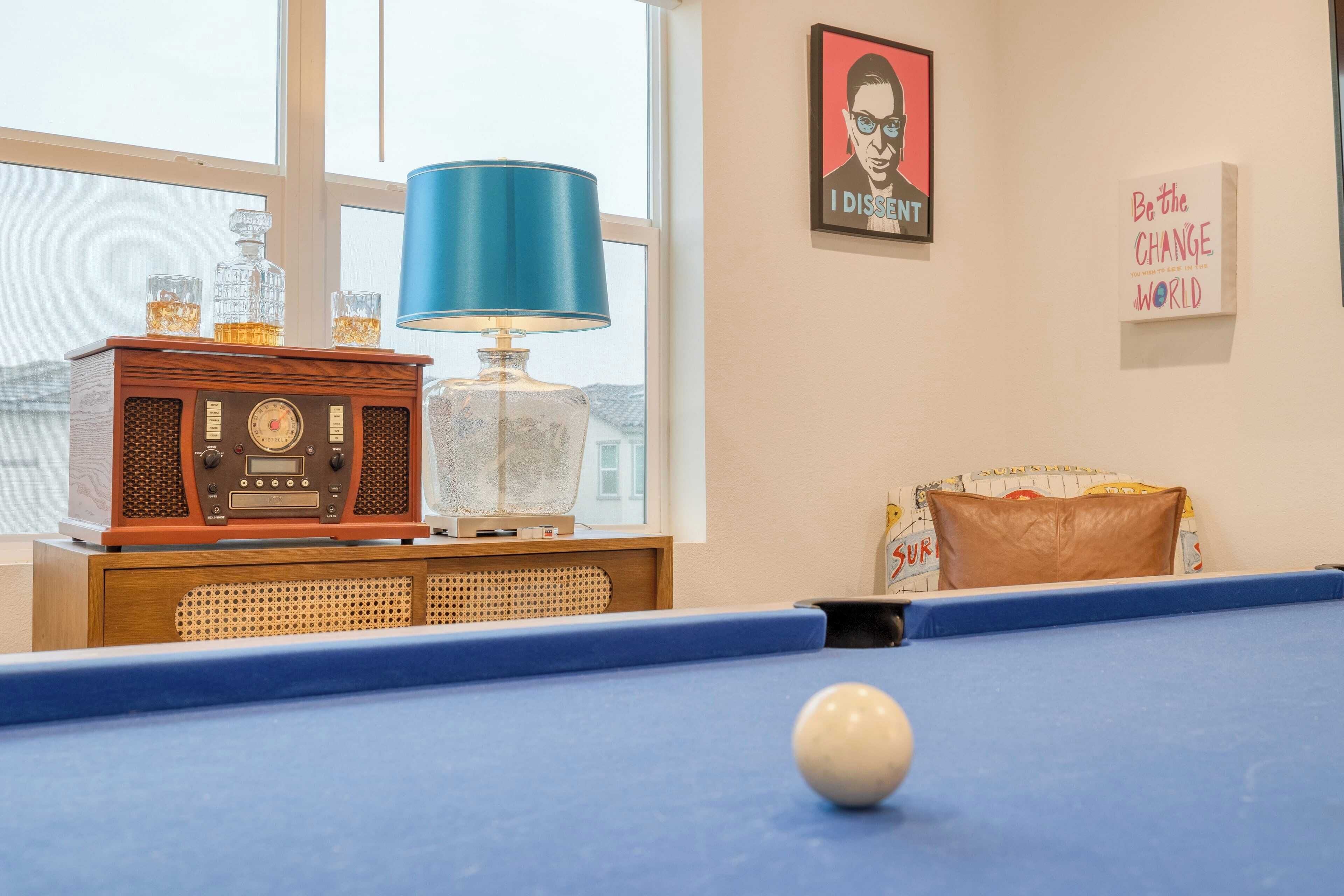 A pool table with a cue ball, a vintage radio, and a blue lamp.