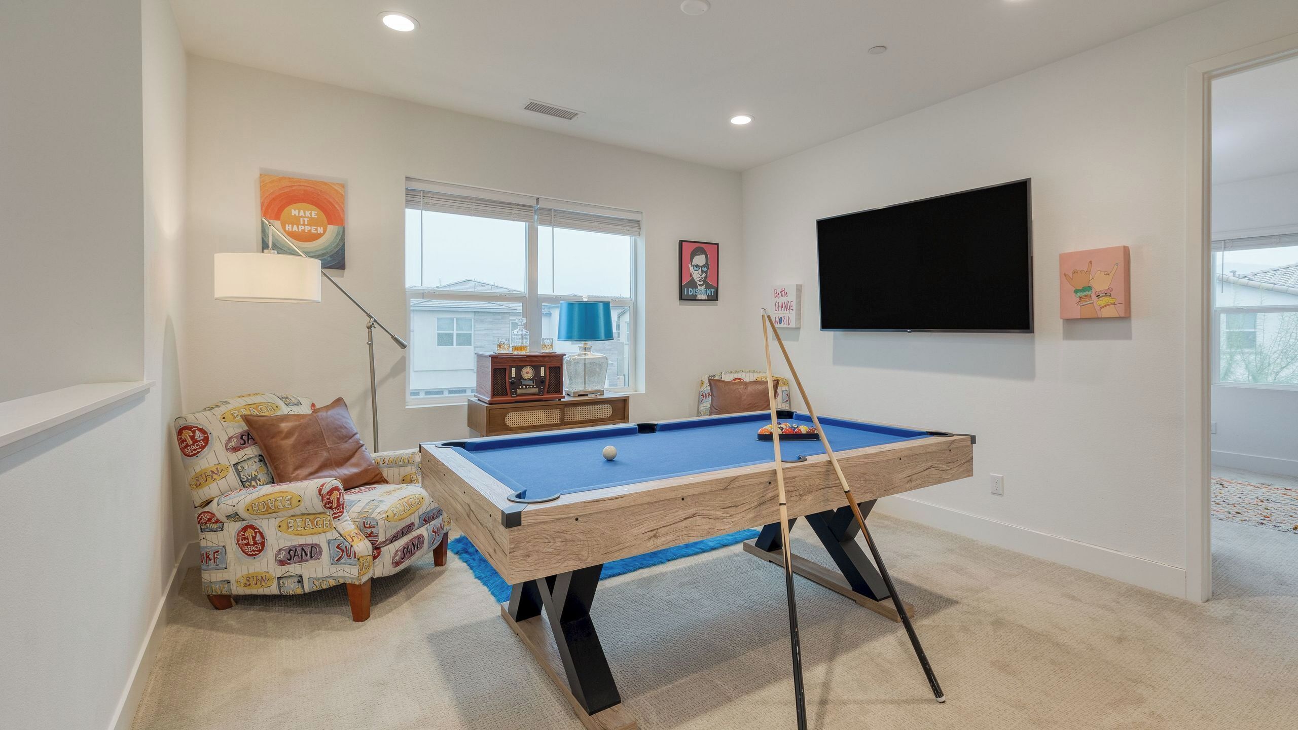 A pool table in a room with a sofa, a television, and a window.