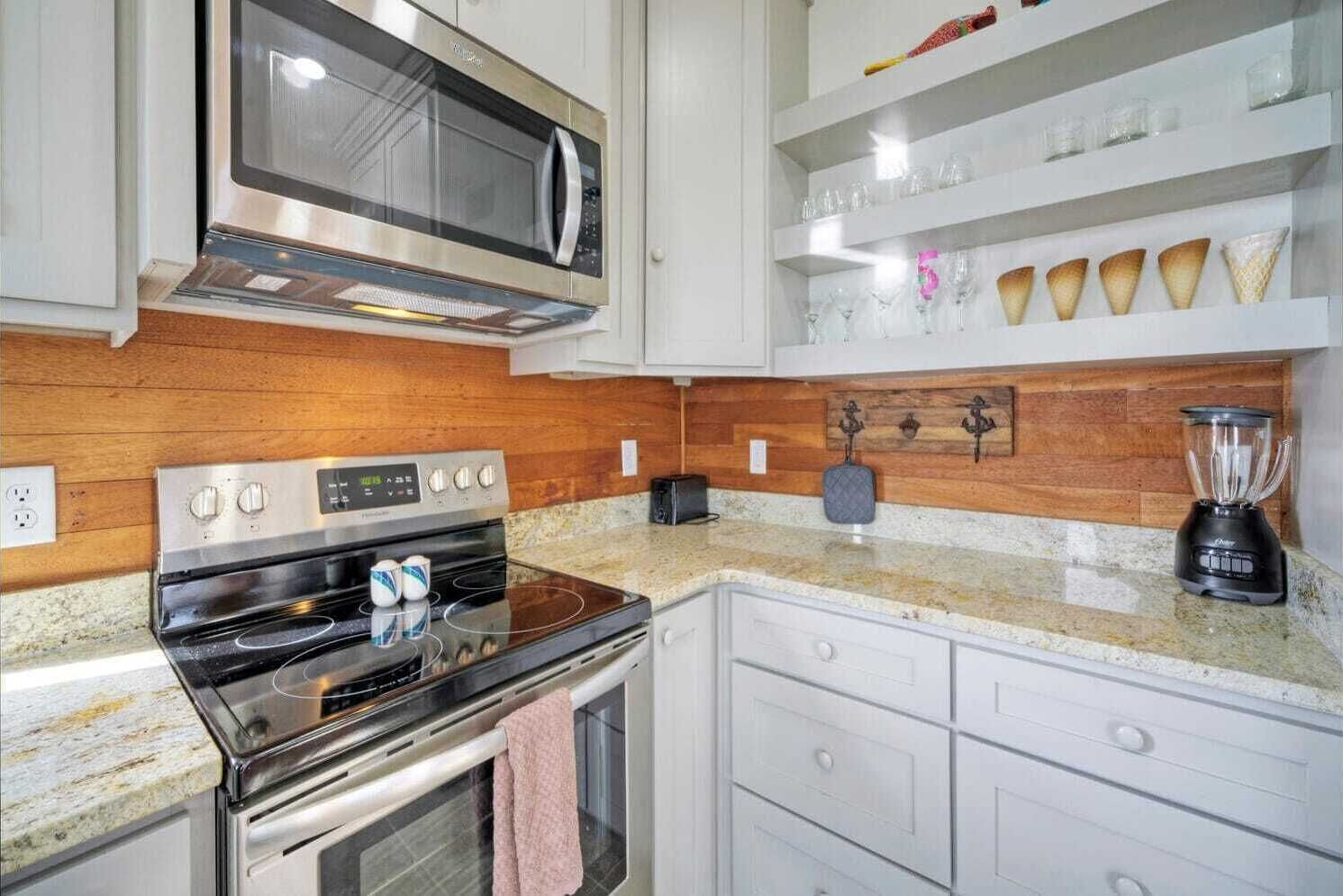Una cocina moderna con electrodomésticos de acero inoxidable, armarios blancos y encimera de granito.
