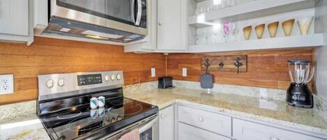 Una cocina moderna con electrodomésticos de acero inoxidable, armarios blancos y encimera de granito.