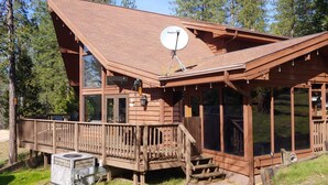 Una baita di legno con veranda, ampie finestre e parabola satellitare.