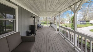 Un portico coperto con una panchina, una TV e un barbecue.
