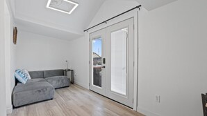 A modern living room with a grey sectional sofa, a small side table, and a sliding glass door leading to a balcony.