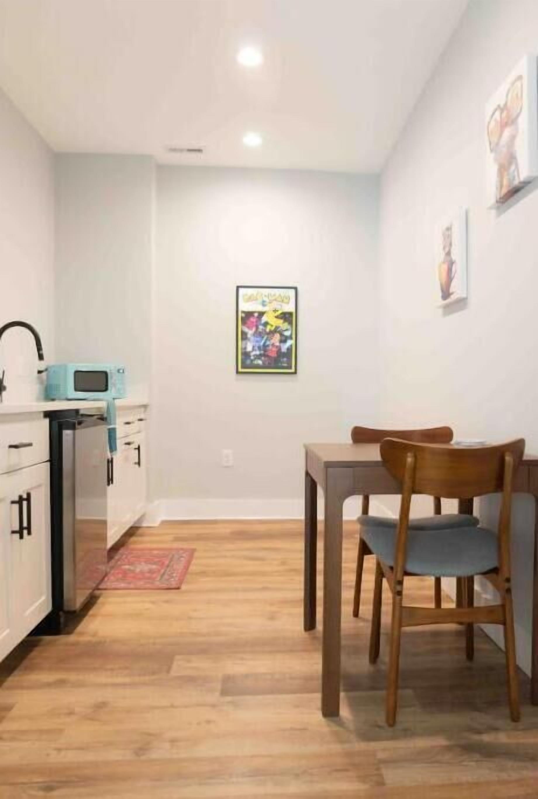 A compact kitchen with white cabinets, a microwave, and a dining area with a table and chairs.