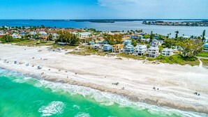 An aerial view of a coastal resort with beachfront properties, a sandy beach, and a clear view of the ocean.