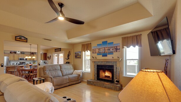 A living room with a fireplace, a ceiling fan, and a television mounted on the wall. - Furnished Patio, Grill & Views: Lake Havasu Home (Lake Havasu City)