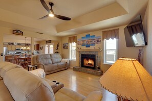A living room with a fireplace, a ceiling fan, and a television mounted on the wall. - Furnished Patio, Grill & Views: Lake Havasu Home (Lake Havasu City)