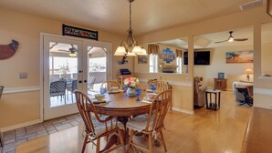 A dining area with a round table, chairs, a chandelier, and a view through glass doors to an outdoor patio. - Furnished Patio, Grill & Views: Lake Havasu Home (Lake Havasu City)