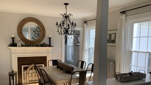 Een eetkamer met een open haard, een kroonluchter en een grote spiegel.