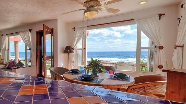 A dining area with a view of the ocean, a ceiling fan, and a tiled bar counter. - Extraordinary Ocean Views - 2 bed / 2 bath and pool (Akumal)