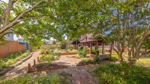 A garden with a brick pathway, wooden pergola, and various plants. - Sea Beauty- MUST SEE 4 BD/ 3 BATH POOL! BCH ACCESS! (Virginia Beach)