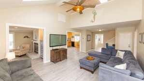 A spacious living room with a large sectional sofa, a flat-screen TV, and a ceiling fan. - Lanikai- POOL/GAME RM/BAY & BCH ACCESS! (Virginia Beach)
