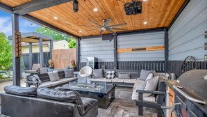 Ein Außenbereich mit Terrasse, einem Deckenventilator, einem Grill und einer Sitzecke mit Sofas und einem Couchtisch.