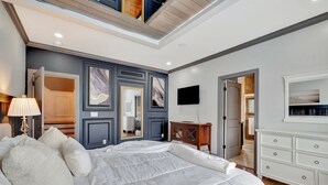 Ein Schlafzimmer mit einem großen Bett, einem an der Wand montierten Fernseher und einem Kleiderschrank.