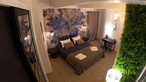 Ein Schlafzimmer mit einem Bett, einem kleinen Tisch, einer Wandlampe und einem grünen Wandpaneel.