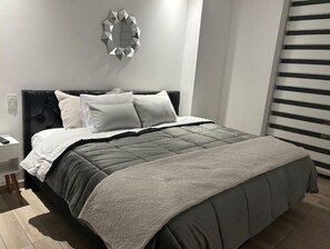 A modern bedroom with a large bed, a headboard, and a decorative wall piece. - All Access _593 Lyfstyle (Quito)