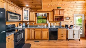 A kitchen with wooden cabinets, a black refrigerator, a microwave, a stove, and a dishwasher.
