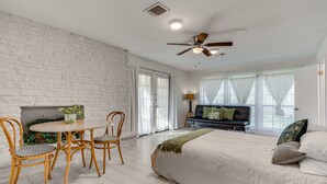 A bedroom with a bed, a dining table with chairs, a sofa, and a fireplace. - Charming Austin Home on 2 Acres: BBQ & Yard! (Austin)