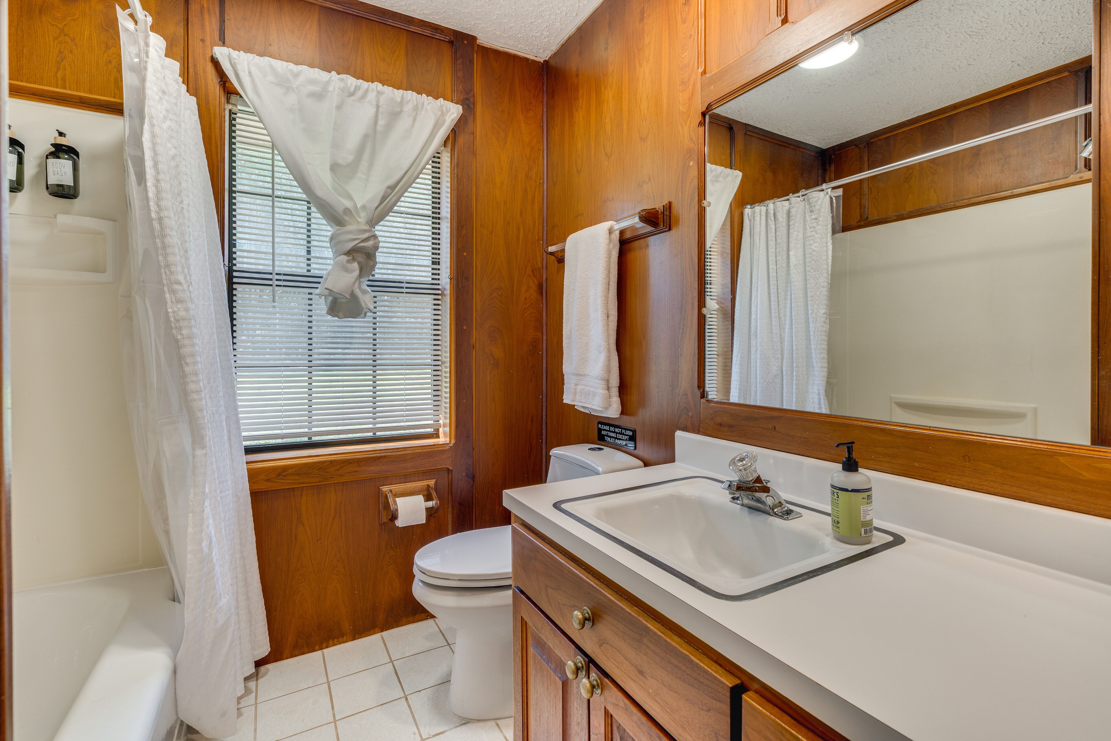 Een badkamer met een houten wastafelmeubel, een wastafel, een spiegel en een toilet.