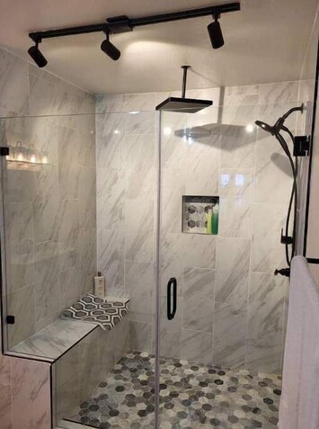 Spacious shower with large shower head above you. Side mounted shower head. 