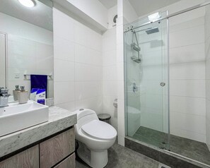 A modern bathroom with a glass-enclosed shower, a white toilet, and a marble countertop. - Keyless 1BR | Ocean View | TV 65" | Peruvian 1606 (Barranco)