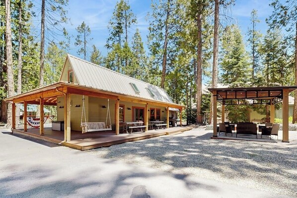 A cabin with a covered porch, outdoor seating, and a gravel driveway.
