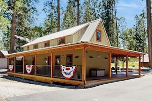 A two-story building with a porch, wooden railings, and a flag.
