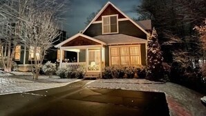 Une maison à deux étages avec un porche à l’avant, un garage et une allée.