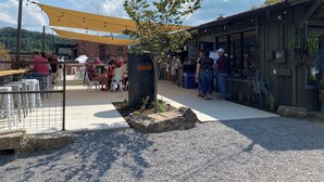 Un espace extérieur aménagé avec des tables et des chaises, un auvent ombragé et un bâtiment sur lequel est apposée une enseigne indiquant « Grange ».