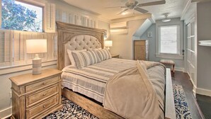 A bedroom with a large bed, a nightstand, a dresser, a ceiling fan, and a window with shutters. - Secluded Retreat with Pool, King Beds in a Historic District, 2 mi from Oaklawn! (Hot Springs)