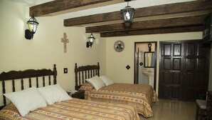 Une chambre avec deux lits, des têtes de lit en bois et une grande porte en bois.