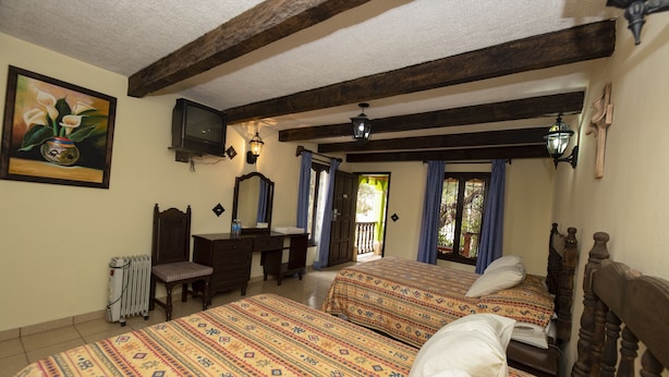 Une chambre avec deux lits, un bureau, une chaise, un radiateur et un téléviseur.