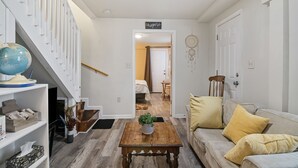 En moderne stue med trappe, et verdenskort, et sofabord med en plante og en sofa med gule puder.