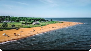 En strand med en lille bygning og grøn bevoksning i baggrunden.