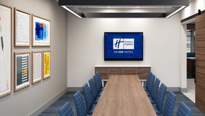 A conference room with a long table, blue chairs, framed artwork on the walls, and a Holiday Inn Express sign on the wall. - Holiday Inn Express Conyers by IHG (Conyers)