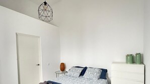 A bedroom with a bed, a bedside table, a lamp, and a dresser. - Apartamento Norte (Arrecife)