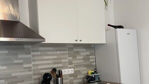 A modern kitchen with white cabinetry, a stainless steel range hood, a built-in stove, a sink, and a refrigerator. - Apartamento Norte (Arrecife)
