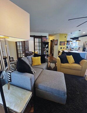 A modern living room with a sectional sofa, a small round table, and a bookshelf.
