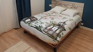Quarto com cama, luminária pendente, parede azul e janela com cortinas.