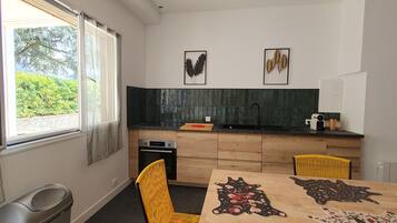 A modern kitchen with a large window, a sink, and a dining table with a unique rug.