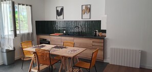 Una cocina moderna con una mesa y sillas de madera, encimera negra y salpicadero verde.