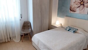 A bedroom with a bed, a chair, a wardrobe, and a painting on the wall. - Betulla Holiday Apartment (Lazise)