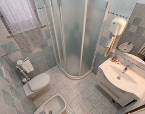 Ein modernes Badezimmer mit einer Duschkabine, einer Toilette, einem Bidet und einem Waschbecken mit Spiegel.