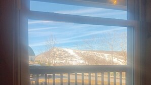 A room with a large window overlooking a snowy landscape and a distant town.