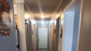 A narrow hallway with wooden flooring, white walls, and a white door at the end.
