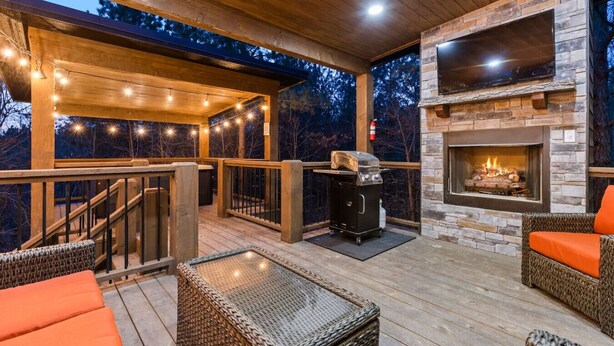 Terraza exterior con chimenea de piedra, mobiliario de mimbre e iluminación con guirnaldas.