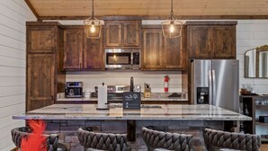 Una cocina moderna con armarios de madera, electrodomésticos de acero inoxidable y una isla central con taburetes de bar.