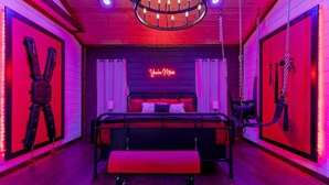 Una habitación con una cama, un banco y un letrero de neón que dice 'You're Mine'.